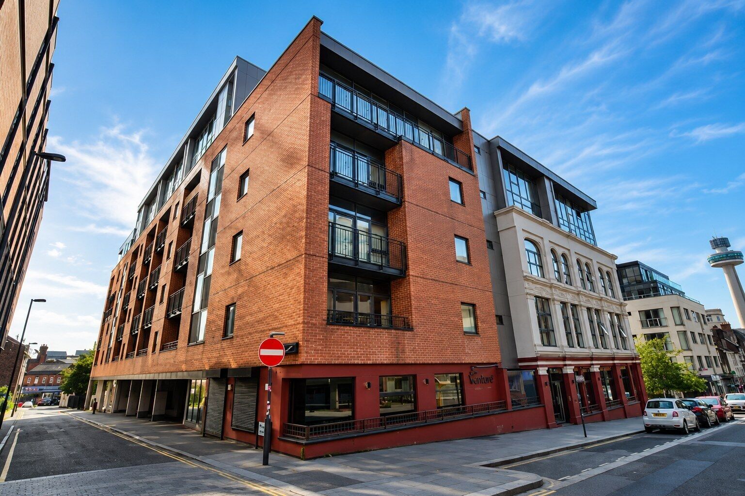 A multi-story building with a brick facade, large windows, and a no entry sign.
