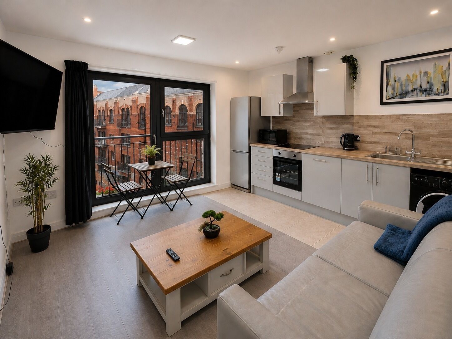 A modern apartment with a balcony, kitchenette, and a sofa.