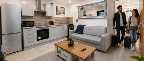 Una cocina moderna con electrodomésticos de acero inoxidable, un sofá gris y una mesa de centro de madera.