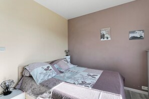 Ein Schlafzimmer mit einem Bett, einem Nachttisch mit Lampe und zwei Bildern an der Wand.