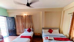 A room with two single beds, a ceiling fan, and a door. - Hotel Forestway Hostel and Backpackers (Pokhara)