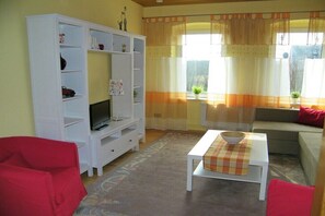 A living room with a white entertainment unit, a television, a sofa, and a coffee table. - The Comfortable Holiday Apartment (Kappeln)