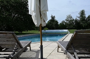 A pool area with lounge chairs and a covered umbrella.