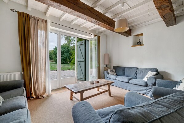 A living room with a sofa, a coffee table, and a view of a garden through a glass door.