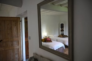 Een kamer met twee bedden, een houten deur en een spiegel die de kamer weerspiegelt.