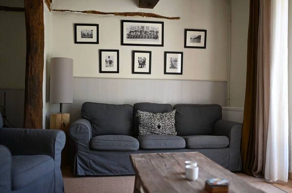 A living room with a grey sofa, a coffee table, and framed pictures on the wall.