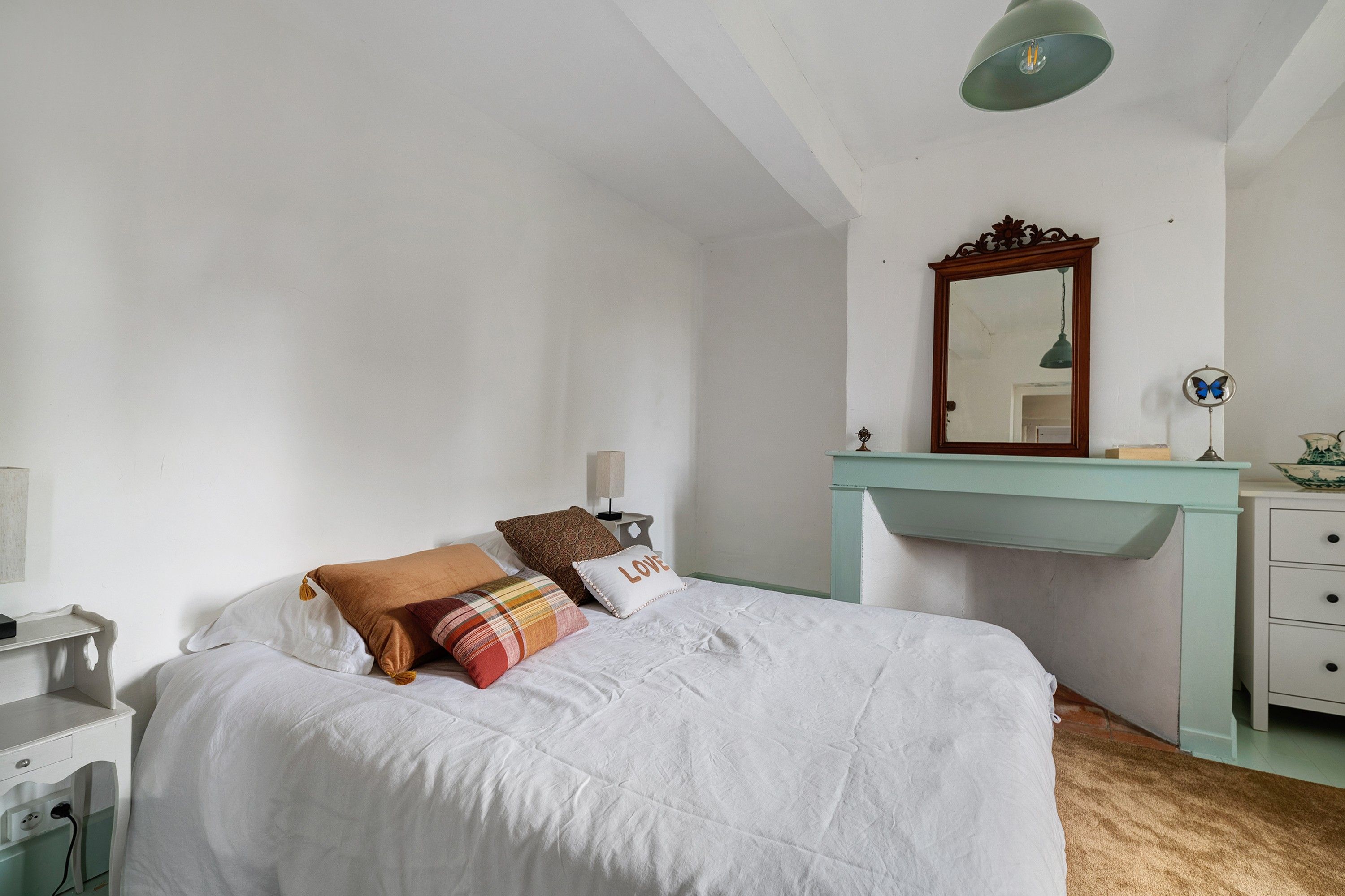 Ein Schlafzimmer mit einem Bett, einer Kommode, einem Spiegel und einem Schreibtisch.