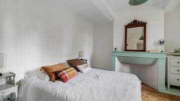 Ein Schlafzimmer mit einem Bett, einer Kommode, einem Spiegel und einem Schreibtisch.