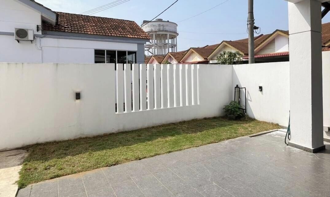 A residential area with a white fence, a paved patio, and a water tower in the background.
