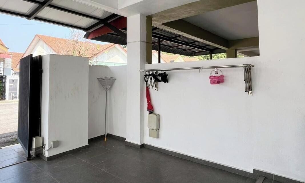 A covered outdoor area with a white wall, a metal railing, and a door.