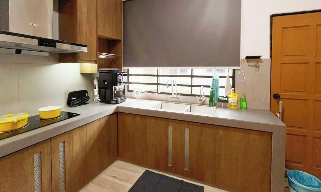 A compact kitchen with wooden cabinets, a coffee maker, and a window with blinds.