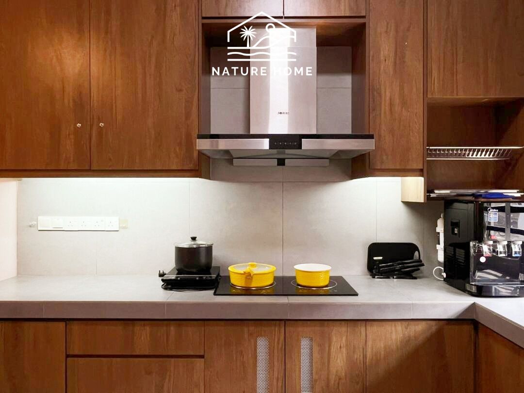 A kitchen with wooden cabinets, a stainless steel range hood, a coffee machine, and two yellow pots on the counter.