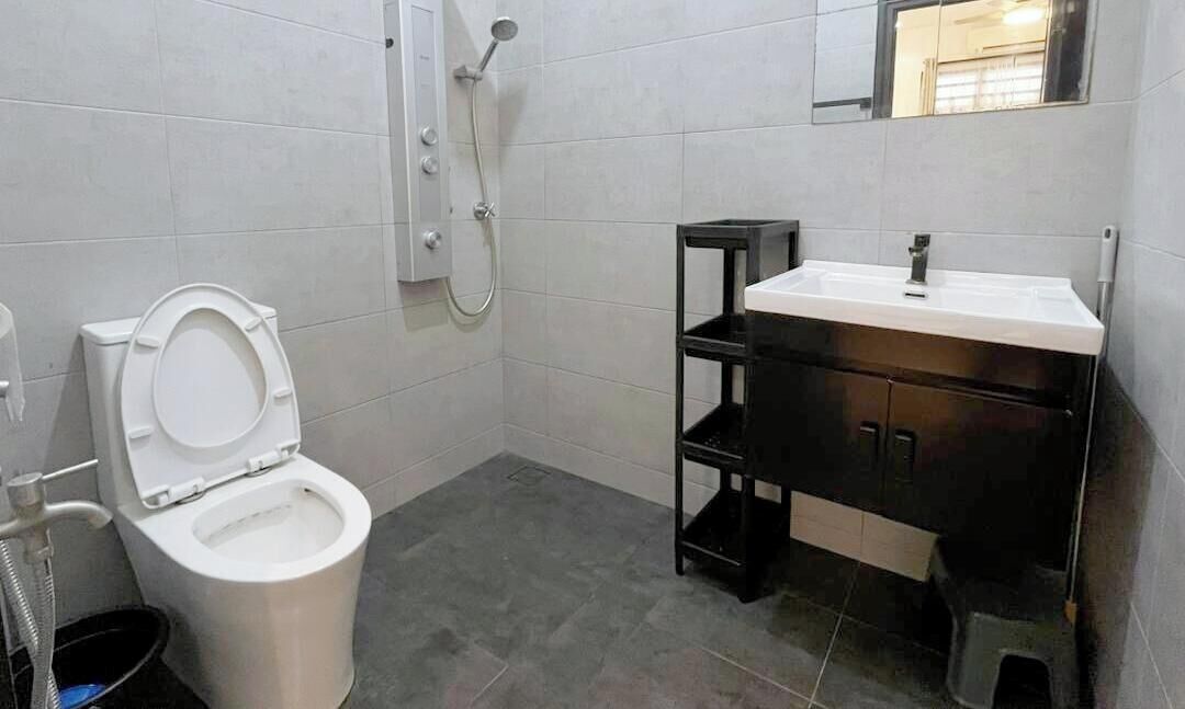 A bathroom with a toilet, a shower, and a sink with a mirror above it.
