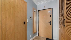 Een gang met een houten garderobe, een deur met een spiegel en een deur met een kruis.