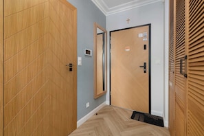 Un pasillo con un armario de madera, una puerta con espejo y una puerta con el símbolo de la cruz.