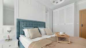 Een slaapkamer met een bed, nachtkastje, lamp, houten deur en een kledingkast.