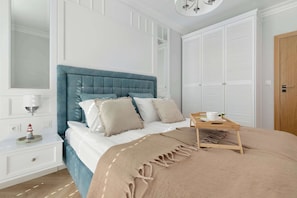Un dormitorio con una cama, una mesita de noche, una lámpara, una puerta de madera y un armario.