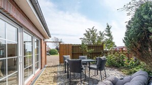 A patio with a table and chairs, a sofa, and a wooden fence. - Holiday apartment with 1 bedroom (Westerdeichstrich)
