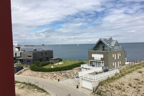 Un immobile costiero con un edificio moderno, vista sul mare e un vialetto che conduce all'ingresso.