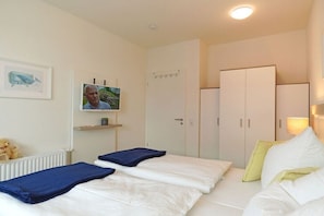 Ein Hotelzimmer mit Bett, Schrank, Ablagefläche mit einem Bild und Heizkörper.