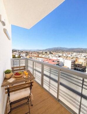 A balcony with a wooden table, a chair, and a potted plant. - Terrasol Jupiter, 9th Floor (Torre del Mar)