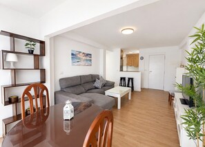 A modern living room with a dining table, sofa, and kitchen area. - Terrasol Jupiter, 9th Floor (Torre del Mar)