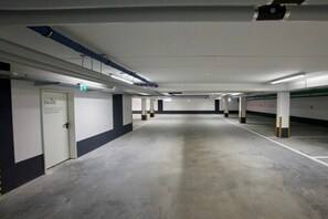 A parking garage with concrete floors, white walls, and pillars with yellow and black stripes. - Bernstein Suite & Breakfast Apartment 04 (Büum)