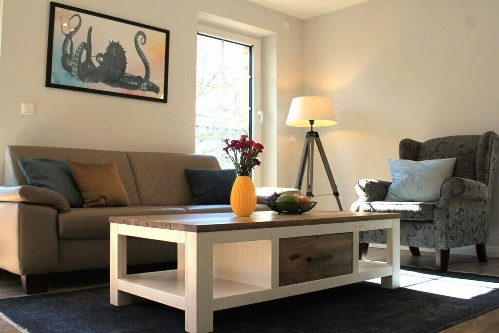 A living room with a sofa, armchair, coffee table, and a lamp.