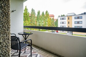 Ein Balkon mit Tisch und Stühlen, mit Blick auf eine Wohngegend mit Bäumen und Gebäuden.