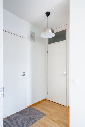 A hallway with two white doors, a light fixture, and a wooden floor.