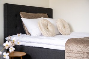 A bed with a dark headboard, white bedding, and two decorative pillows. - Nordic City Studio By Lapland Host (Rovaniemi)