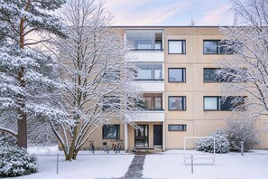 A multi-story building with a snow-covered exterior, a visible entrance, and a bicycle parked outside. - Nordic City Studio By Lapland Host (Rovaniemi)