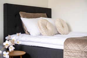 Ein Bett mit dunklem Kopfteil, weißer Bettwäsche und zwei Zierkissen.