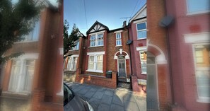 A two-story brick house with a front door, windows, and a visible garage door. - Spacious 3BDR Home with Garden in North London (Greater London)