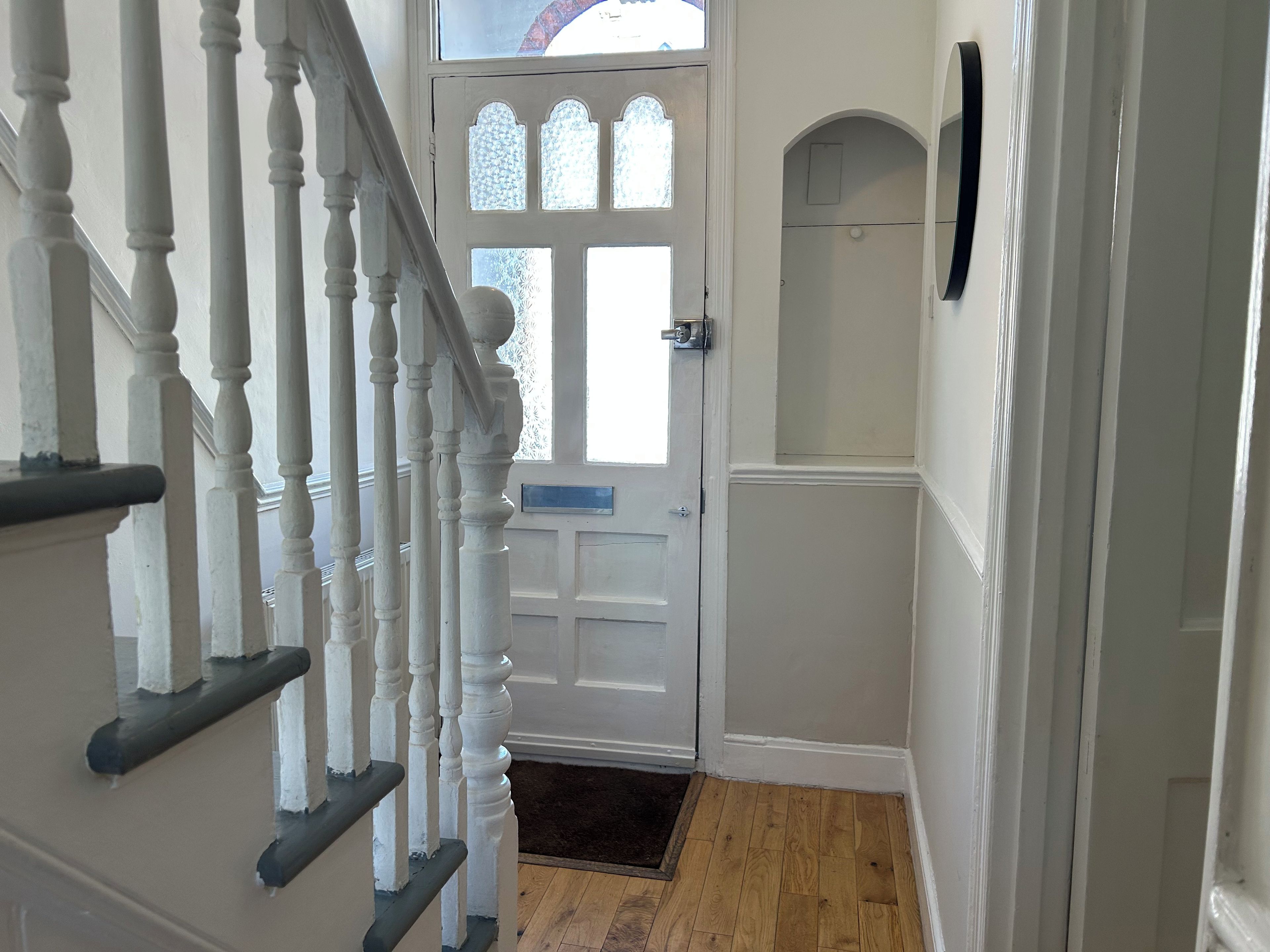 A staircase with white balusters leading to a door with a frosted glass window.