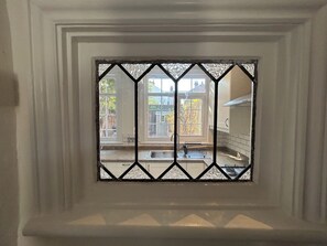 A window with a diamond-patterned grille, a kitchen area with a sink and cabinets, and a view of the outside. - Spacious 3BDR Home with Garden in North London (Greater London)
