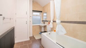 Et badeværelse med badekar, vask og toilet.