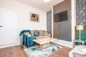 Ein modernes Wohnzimmer mit einer Couch, einem Couchtisch, einem gemusterten Teppich und einer dekorativen Lampe.
