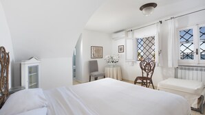 Un dormitorio con cama, una silla, una mesa y un ventanal con vistas.