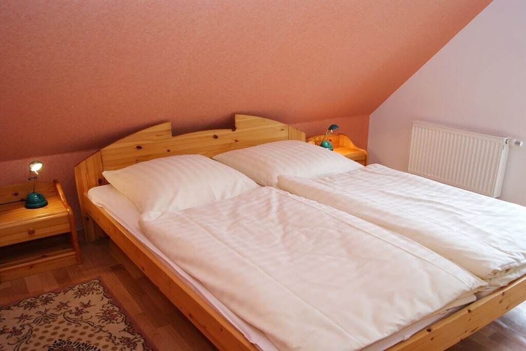 A single bed with a wooden headboard in a room with a sloped ceiling.
