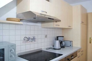 A kitchen with a built-in stove, a coffee maker, and a toaster. - Holiday apartment in Dierhagen with balcony (Dierhagen)