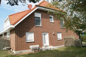 Ein Backsteinhaus mit rotem Ziegeldach, einer Satellitenschüssel und einem Holztor.