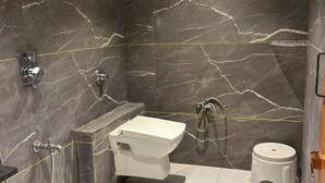 A bathroom with a marble sink, a toilet, and a shower area. - KOKO Regency Hotel & Hospitality (Gandhinagar)