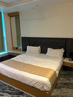 Ett hotellrum med en stor säng, ett sängbord och en spegel.