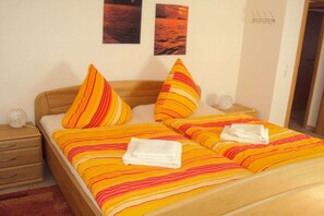 A hotel room with a bed, two pillows, a nightstand, a lamp, and two wall-mounted pictures. - Holiday home with 1 bedroom (Mettlach-Tünsdorf)
