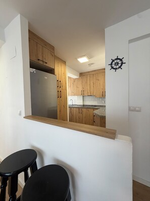 Cuina moderna amb armaris de fusta, un frigorífic d'acer inoxidable i una decoració de timó de vaixell a la paret.