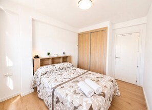 Un dormitori amb un llit, una taula de nit, un armari i una porta.