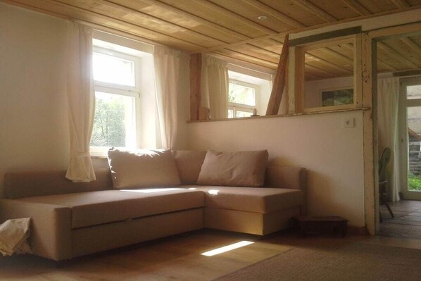 Una habitación con un sofá color beige, una mesita y una ventana con cortinas.