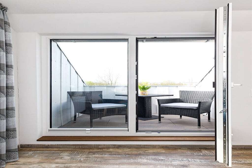 A room with a sliding glass door leading to an outdoor seating area with two chairs and a table.