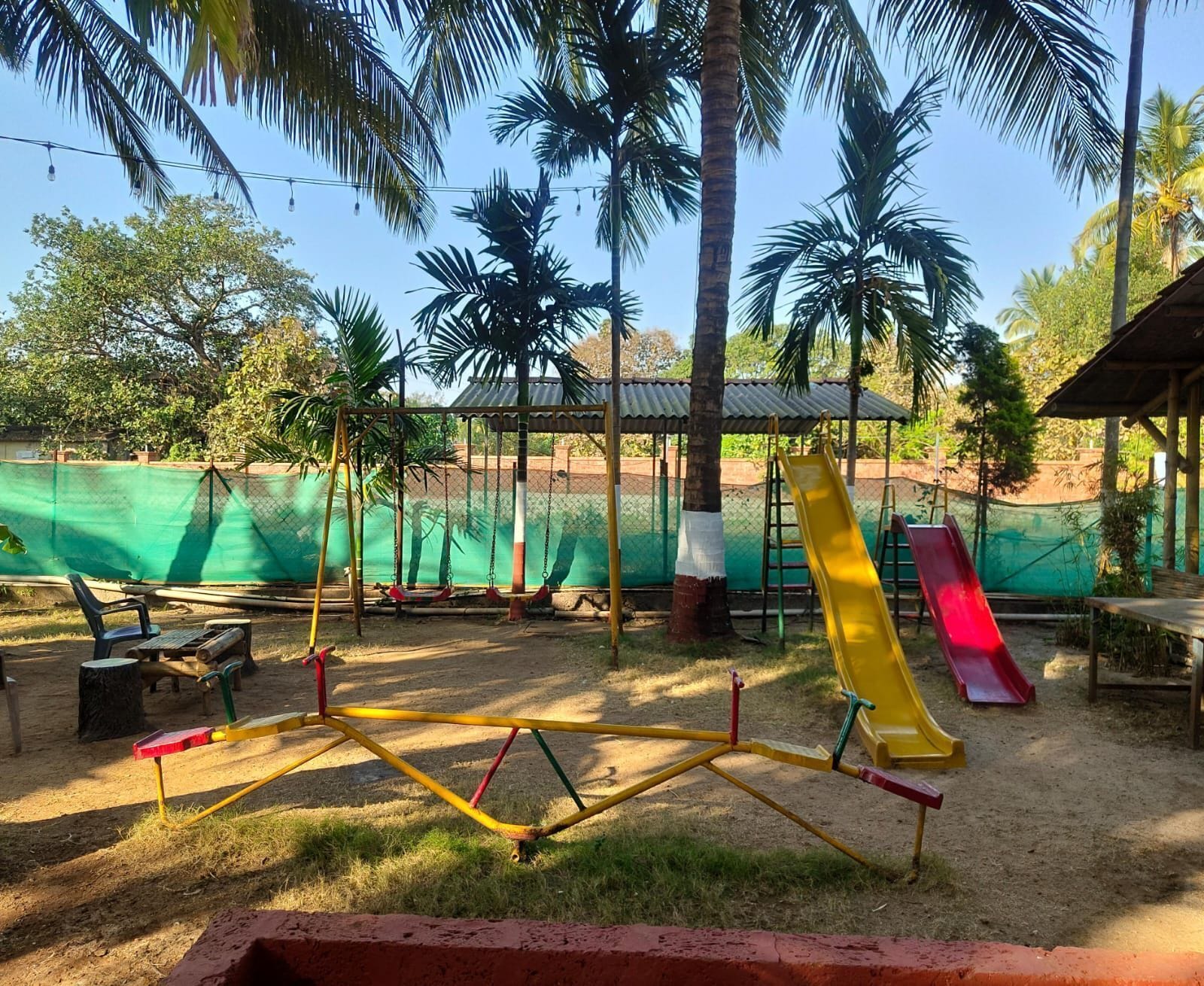 Un parque infantil con columpios, toboganes y una zona vallada.